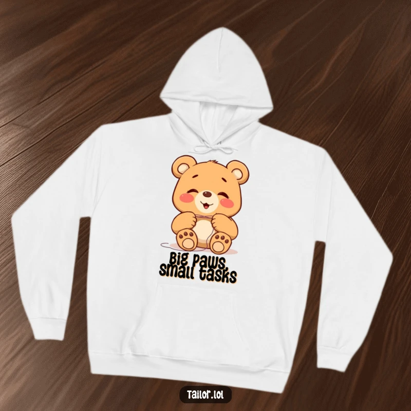 Funny giggling bear character with big paws trying to thread a tiny needle, featured on a cozy hoodie, a humorous gift idea.